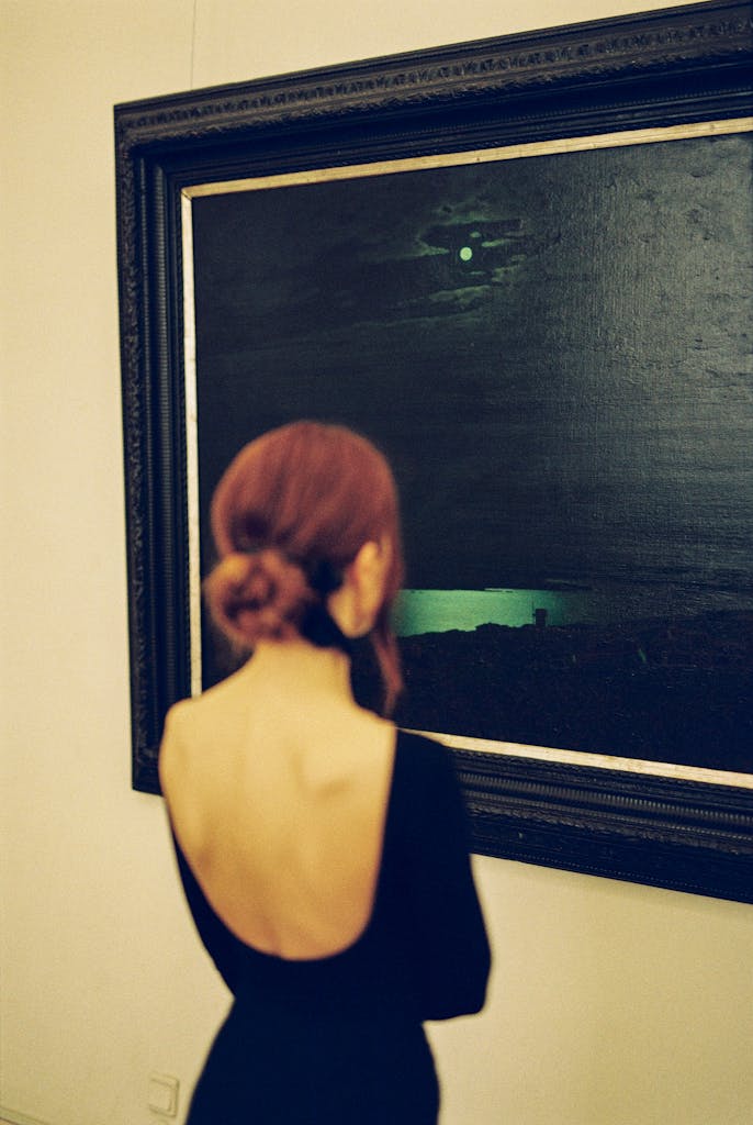 A woman observes a painting in an art gallery, creating a contemplative atmosphere. Photo by Vladimir Konoplev.